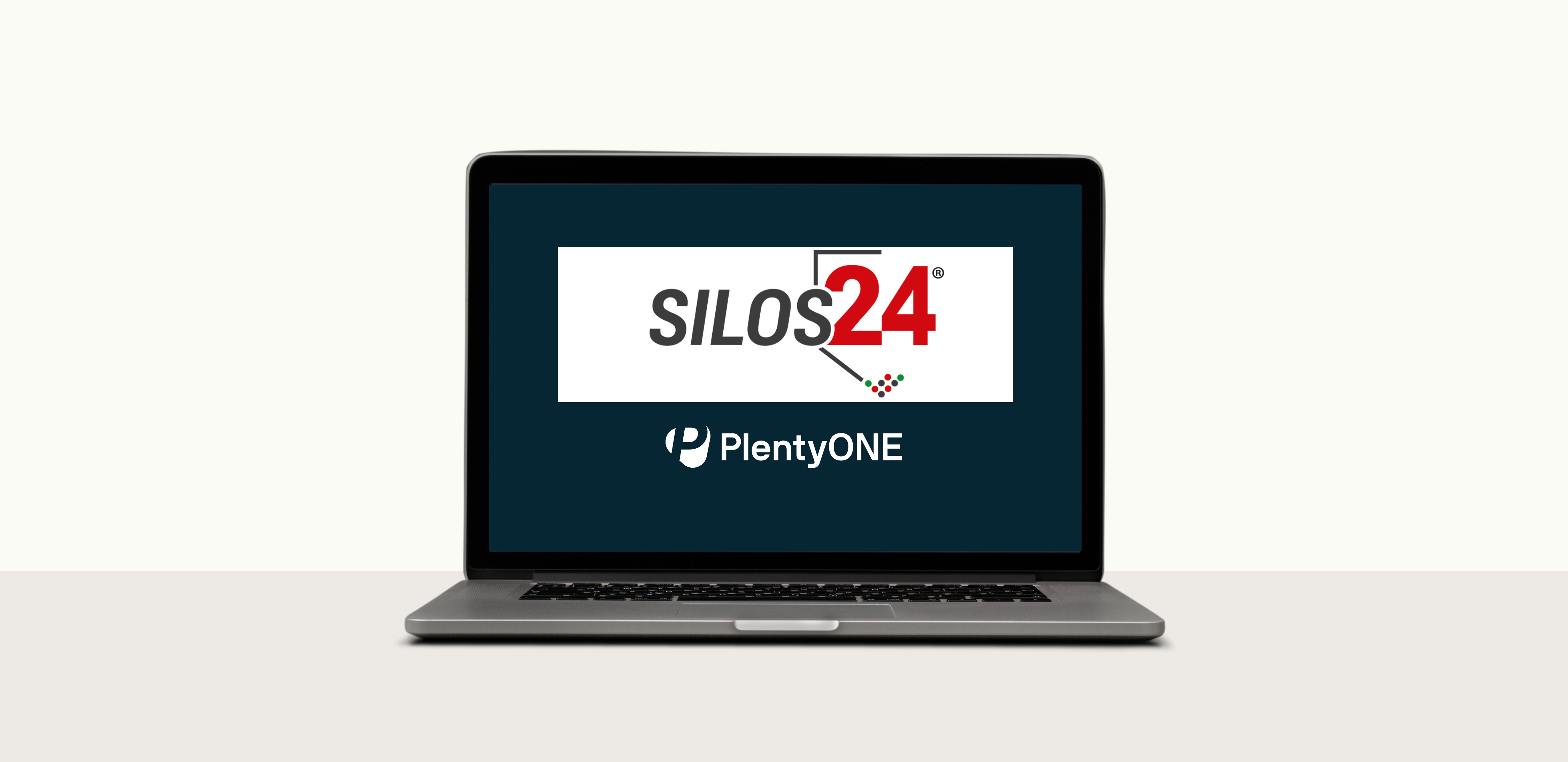 Ein MacBook-Laptop, dessen Bildschirm eingeschaltet ist und einen dunkelblauen Hintergrund anzeigt. Das Logo von Silos24 ist in einem weißen Rechteck in der Mitte zu sehen. Das Logo zeigt das Wort „SILOS“ in Grau und „24“ in Rot mit einem stilisierten Haus-Icon. Darunter befindet sich das Logo von PlentyONE. Der Laptop steht auf einer hellgrauen Oberfläche vor einem schlichten weißen Hintergrund.